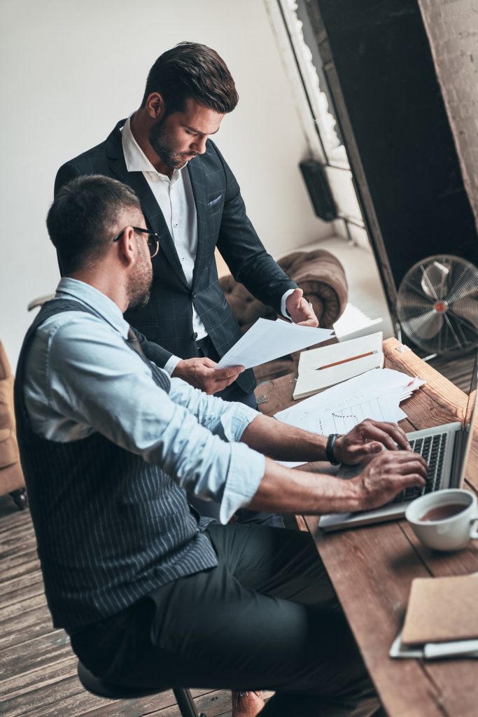 Giving business advice. Two young modern men in formalwear working together while sitting indoors